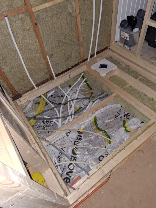 Trästomme med isolering i ett badrumsbygge där golvisoleringen saknar luftgap mot marken.