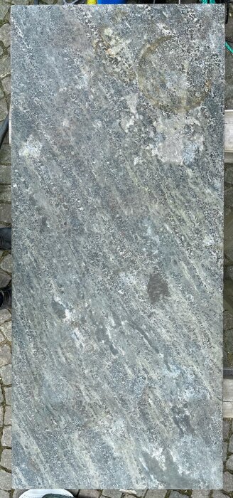 Polerad kolmårdsmarmorplatta med synliga mönster och ringar, fotograferad ovanifrån.