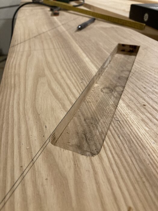 Utskuret spår i trappsteg av trä med brännmärken, verktyg i bakgrunden.