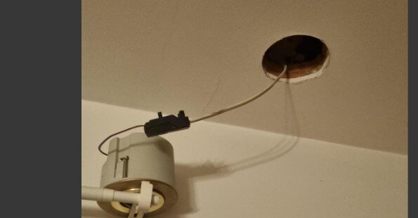 Takspotlight som hänger ner från hål i taket med en synlig kabel.