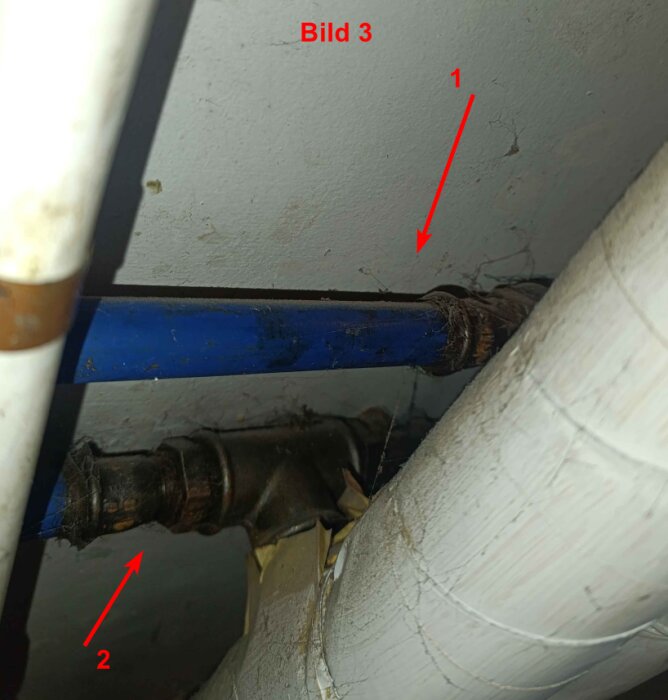 Bilden visar två rör anslutna till ett T-kopplingsrör, där rör 1 är blått och rör 2 är mörkare, med märken och spindelväv runt.