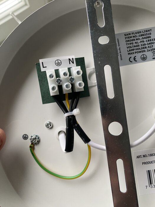 Ny lampa med kopplingsplint för N, L och jord. Orange kabel diskuteras. E27 lamphållare, maxeffekt 2x25W, monteringsfäste synligt.