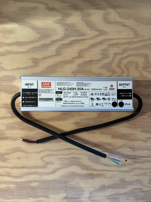 MeanWell HLG-240H-30A LED-drivdon med exponerade kablar, liggande på en ljus träyta.