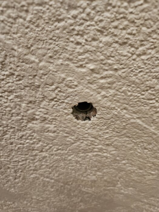 Hål i vägg med synlig expanderhylsa efter borttagen boxboll.