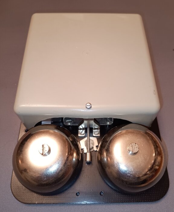 Ringklocka DeTeWe 1 från 1964 med två silverklockor och vit skyddsplatta.