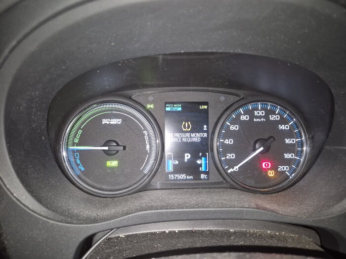 Instrumentpanel i bil med varningar för däcktryck och handbroms.