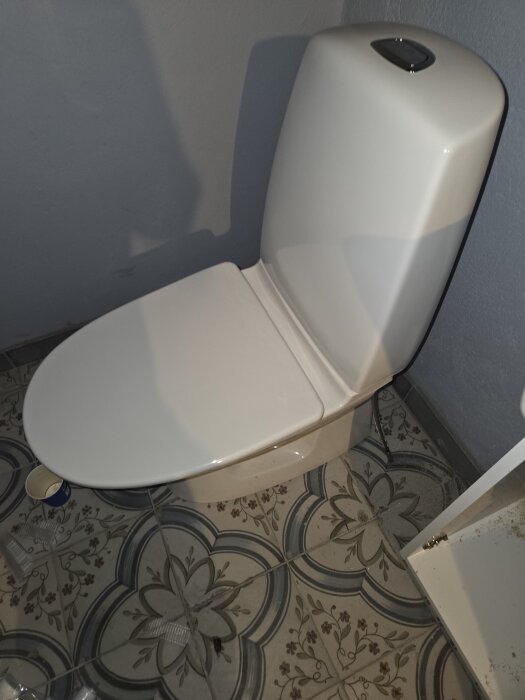 Vit ifö rimfree toalett installerad på ett dekorativt kakelgolv i ett källarbadrum.