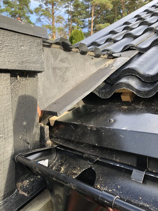 Fotplåt på tak med synlig gammal takpapp mellan fotplåt och hängränna, vilket verkar felplacerat.