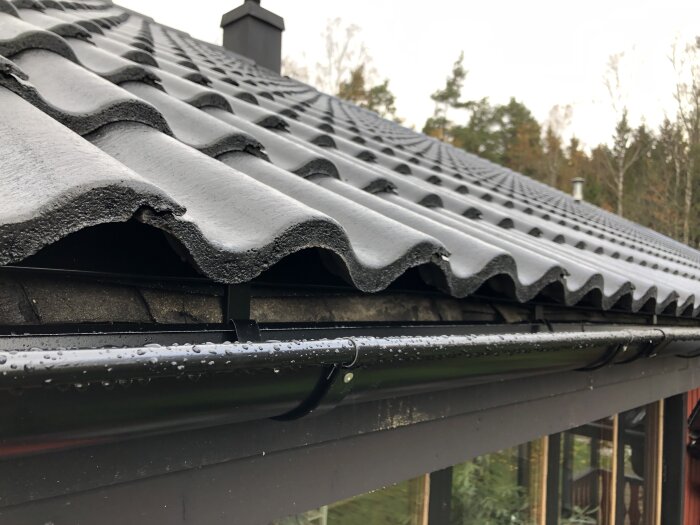 Tak med tegelpannor, fotplåt delvis täcker gammal takpapp, synlig mellan fotplåt och hängränna. Fråga om installationens korrekthet.