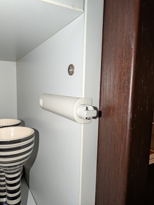 Push-to-open mekanism i skåp med roterande hake.