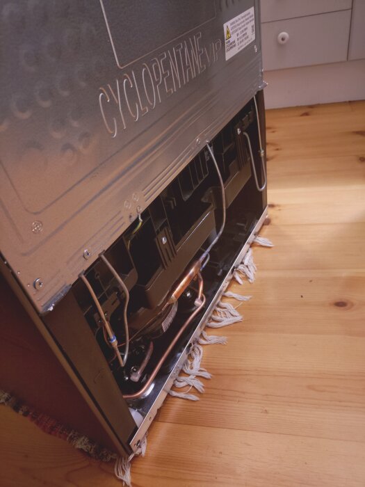 Baksidan av en Samsung-frys med exponerade kopparrör och utan skyddsplåt.