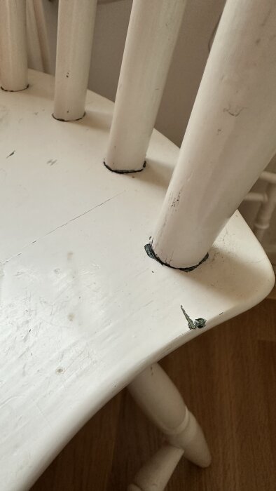 Vit stol med repor och slitage, synliga skavanker vid benen.