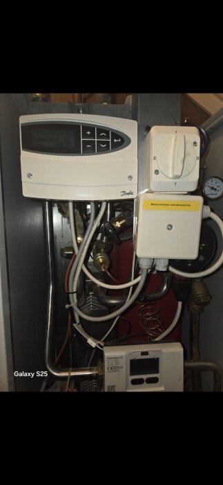 Värmecentralpanel och påfyllningsventil i en villa från 2009, med manöverpanel inzoomad och kopplingar synliga.