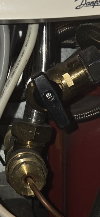 Närbild av en påfyllningsventil i en villa från 2009 med koppar- och plastslangar anslutna.