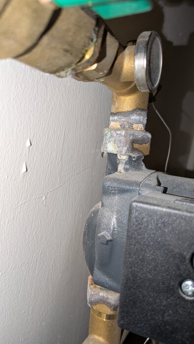 Anslutning till golvvärmepump med tecken på läckage och rost.