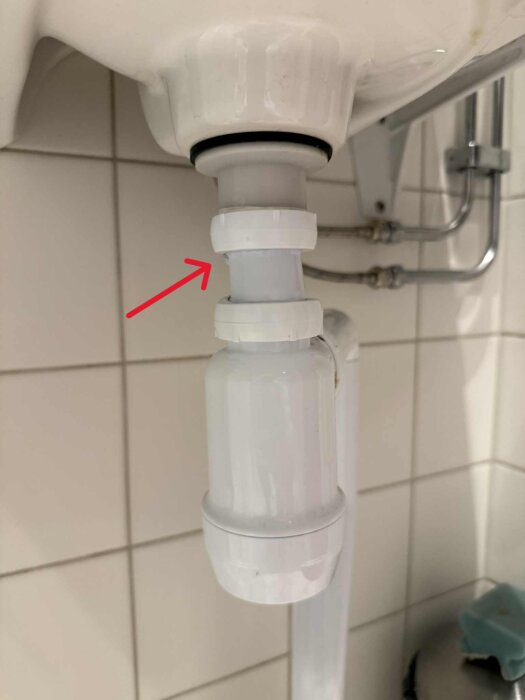 Närbild på ett underhandfat avloppsrör med ett rött markeringsfält vid en koppling ovanför vattenlåset, eventuellt läckage indikeras.