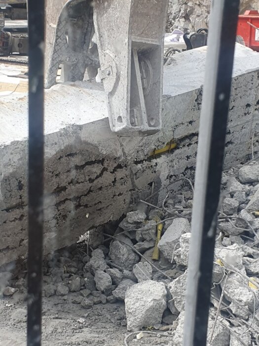 En armerad betongplatta har brutits upp och ligger ovanpå en hög av betongspill och synliga rör, vilket pekar på byggfel.