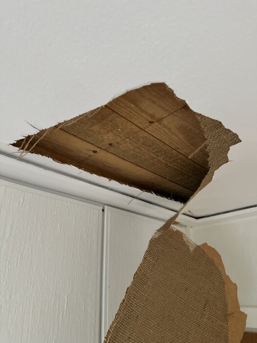 Rivet vävtak visar träplankor under i ett sovrum.