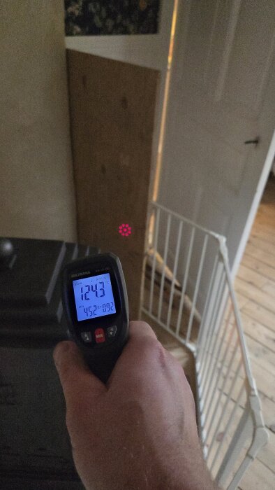 Termometer visar 124,3 grader på plywoodskiva nära kamin, planerad hyllplats; avstånd till kamin 30 cm.