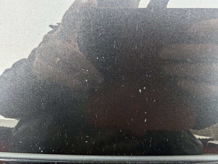 Närbild av motorhuv med tydliga lackskador och reflexioner, vilket kan ses i en diskussion om bilskador och försäkringsbesiktning.