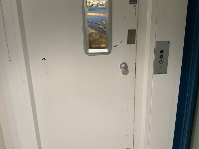 Hissdörr med glasruta och knappar; frågeställning om asbest närvarande på en skola.