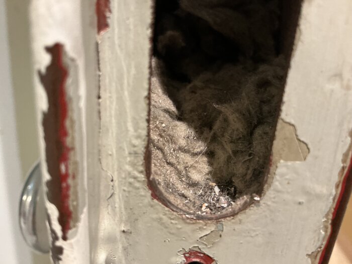 Närbild av material inuti en hissdörr på en skola, som kan misstänkas vara asbest.