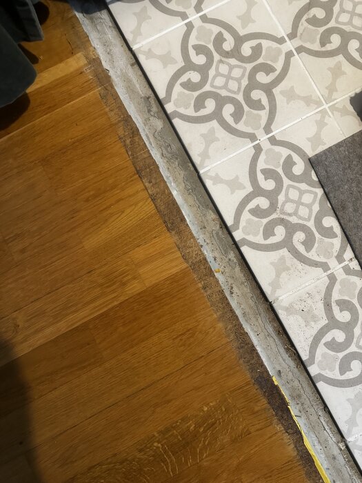 Övergång mellan klinkers och parkett, där en list saknas och avståndet syns tydligt. Olika tjocklekar skapar ett glapp mellan materialen.