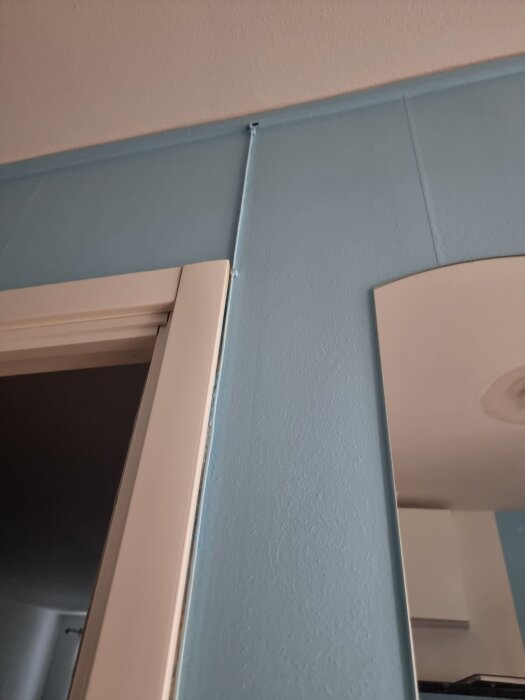 Vägg i hall med blå färg och avklippt kabel ovanför dörrkarm, del av ett gammalt telefonjack.