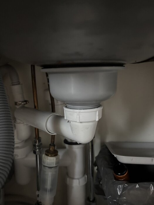 Läckande avloppsrör under vask med anslutning mellan grått och vitt rör. Byte av packning har inte löst problemet.