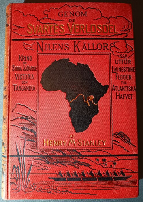 Röd bokomslag av "Genom de Svartes Verldsdel, Nilens Källor" av Henry M. Stanley, med karta över Afrika och illustration av roddbåt.