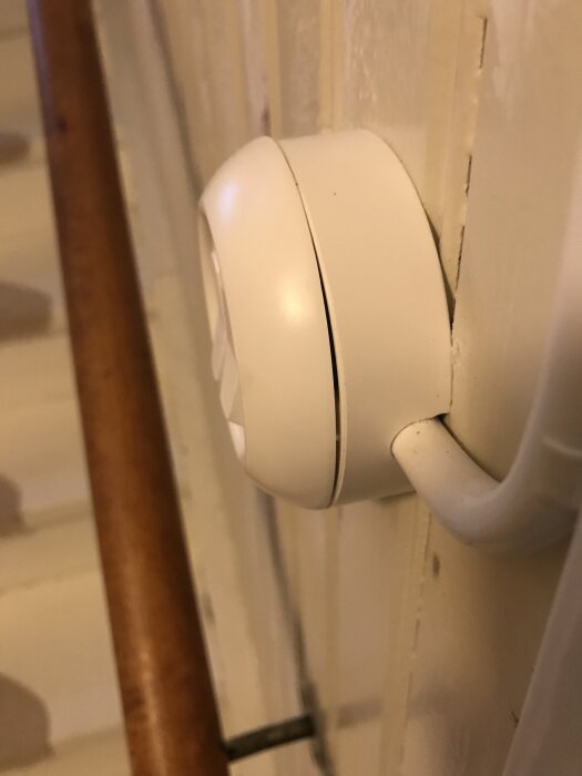 Vit strömbrytare på en vägg med ett synligt glapp mellan ringen och hållaren.