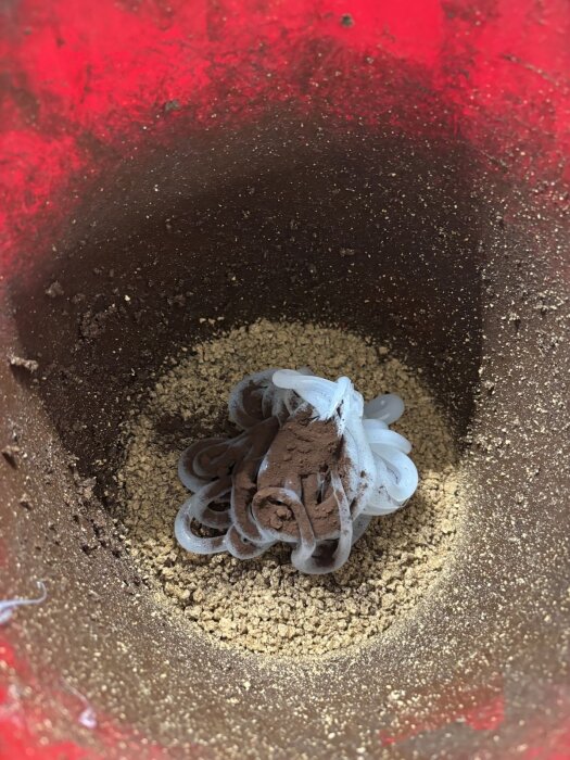 Malda korksmulor och silikonkräm i en röd behållare för att göra korkkomposit till väggbeklädnad i ett husvagnsprojekt.