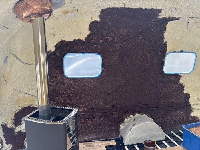 Invändigt av en husvagn med bruna väggar av korkblandning runt fönster, skorstensrör och en eldstad.