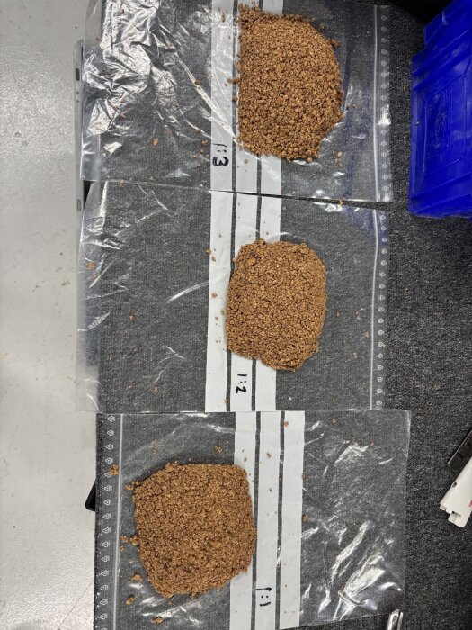 Tre provbitar av kork och silikonblandningar märkta med olika proportioner på plastpåsar för test av rätt blandningsförhållande.