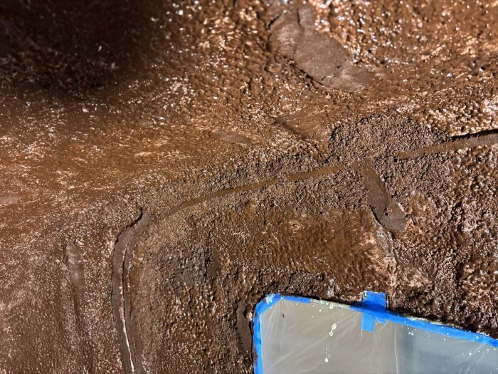 Brun yta av kork och silikon på en vägg, applicerat för att jämna ut ojämnheter inför vidare byggarbete i en husvagn.