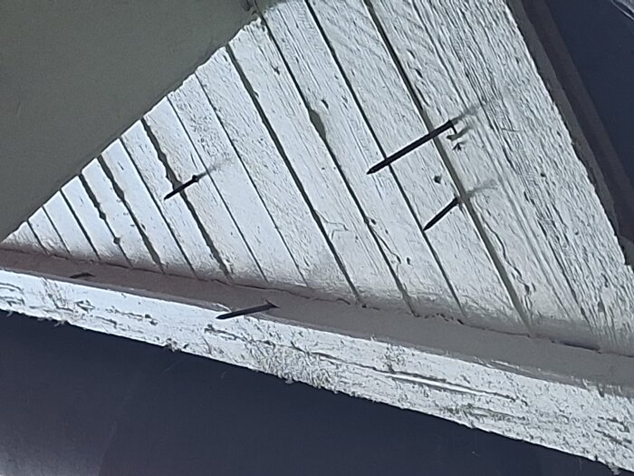 Brädor i ett tak med spikar som sticker ut på undersidan, vilket kan indikera fusk vid takläggning.