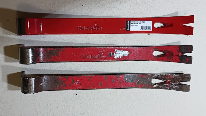 Tre röda bärgningsjärn av märket Hultafors, varav det översta är nytt, placerade på en vit bakgrund.