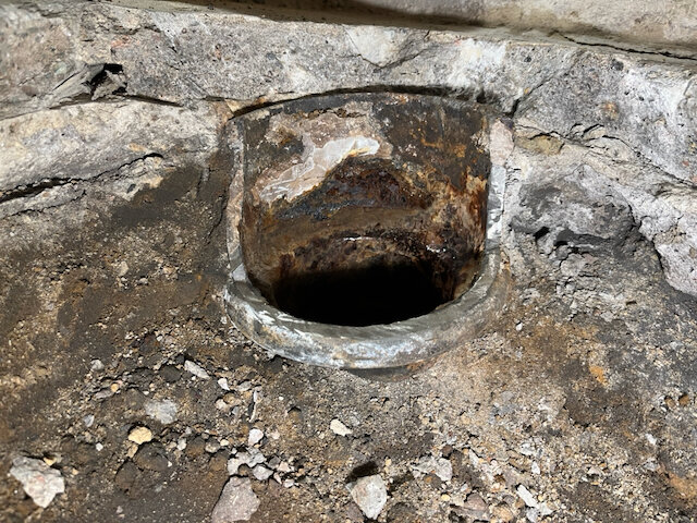 Kapat rör i mark med synlig rost och smuts runt omkring. Rörets innerdimension är omkring 90-95 mm.