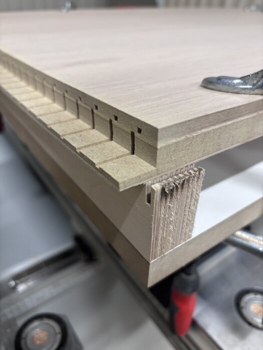 Böjd kantlist med fasning syns från sidan, hålls fast med klämma. Bearbetning av svängd lucka under byggprojekt.