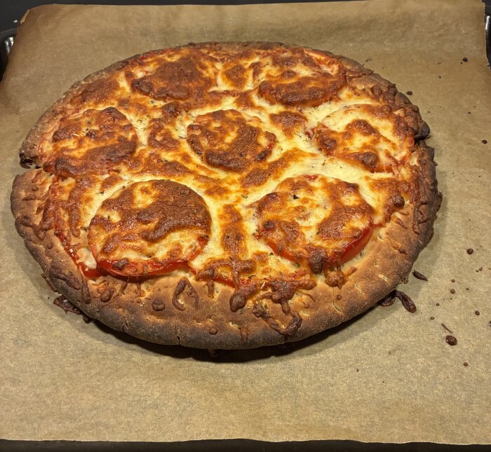Hemlagad pizza med brunt, smält ost på bakplåtspapper, ser lite bränd ut men beskrivs som saftig inuti.