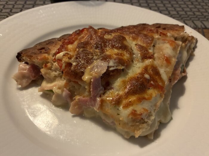Hemmagjord tårtpizza med skinka och ost på en tallrik, med krispig, gyllenbrun yta.