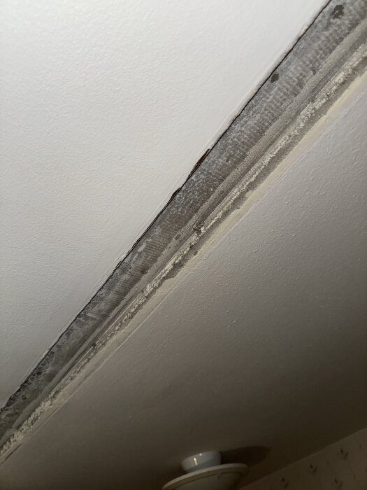 Tak med en fåra där en skiljevägg tagits ner, synligt markant djup där taket är ojämnt mellan hall och kök.