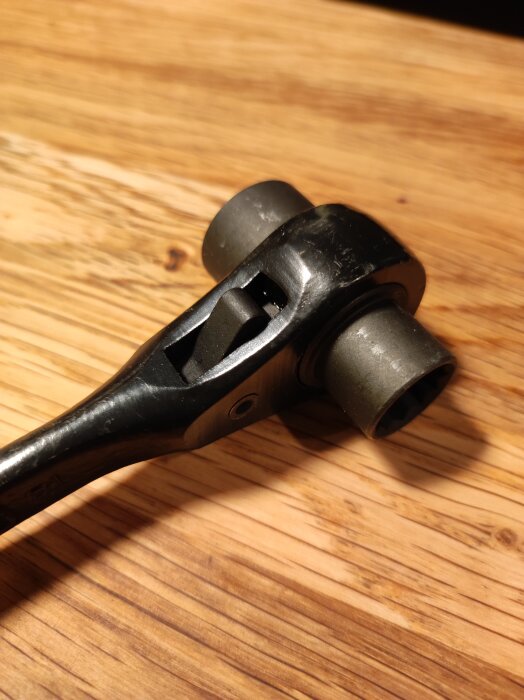 En svart spärrnyckel med dubbla hylsor för M8 och M10 skruvar, liggande på ett träbord. Märke: Super, Made in Japan.