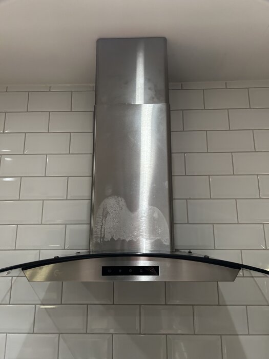 Köksfläkt av modell Thermex Optica 662 med kondens på stålkåpan, monterad mot vit kakelvägg.