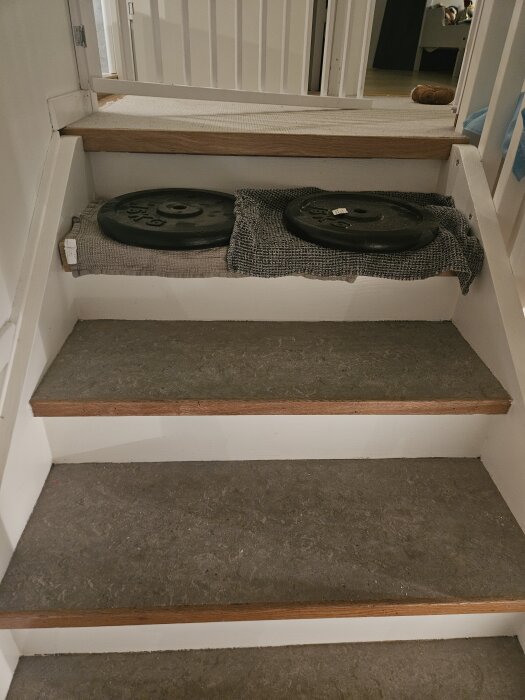 Trappa med linoleummatta, vikta vikter överst för att pressa fast ny trappnos, del av trapprenovering på budget.