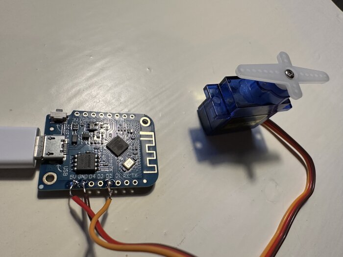 Mikrokontrollerkort anslutet till ett microservomotor, kablar lödda på kretskortet.