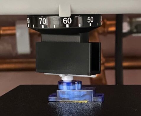 Bild på en blå servoarm fäst på en plattform med en svart ratt överst, del av ett projekt för att tillverka en U-profil för att vrida ratten.