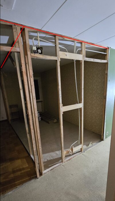 Väggstomme med reglar markerad med rött, visar träkonstruktion med elledningar, osäker på om bärande; inkluderar synliga tak och golv i ett rum.