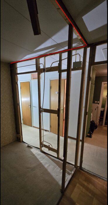 Oisolerad väggstomme med 4x4 cm reglar, markerad med röda linjer i ett rum med flera dörrar synliga i bakgrunden.