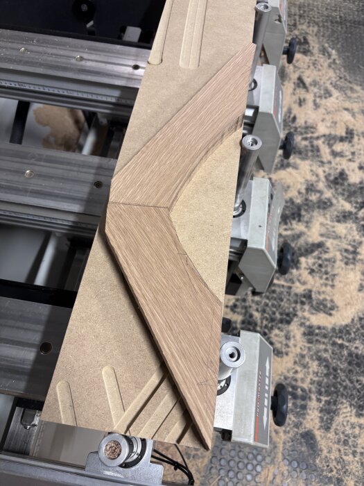 Falsad kantlist tillverkad av trä, ligger fastspänd på en arbetsbänk med metallklämmor, redo för limning.